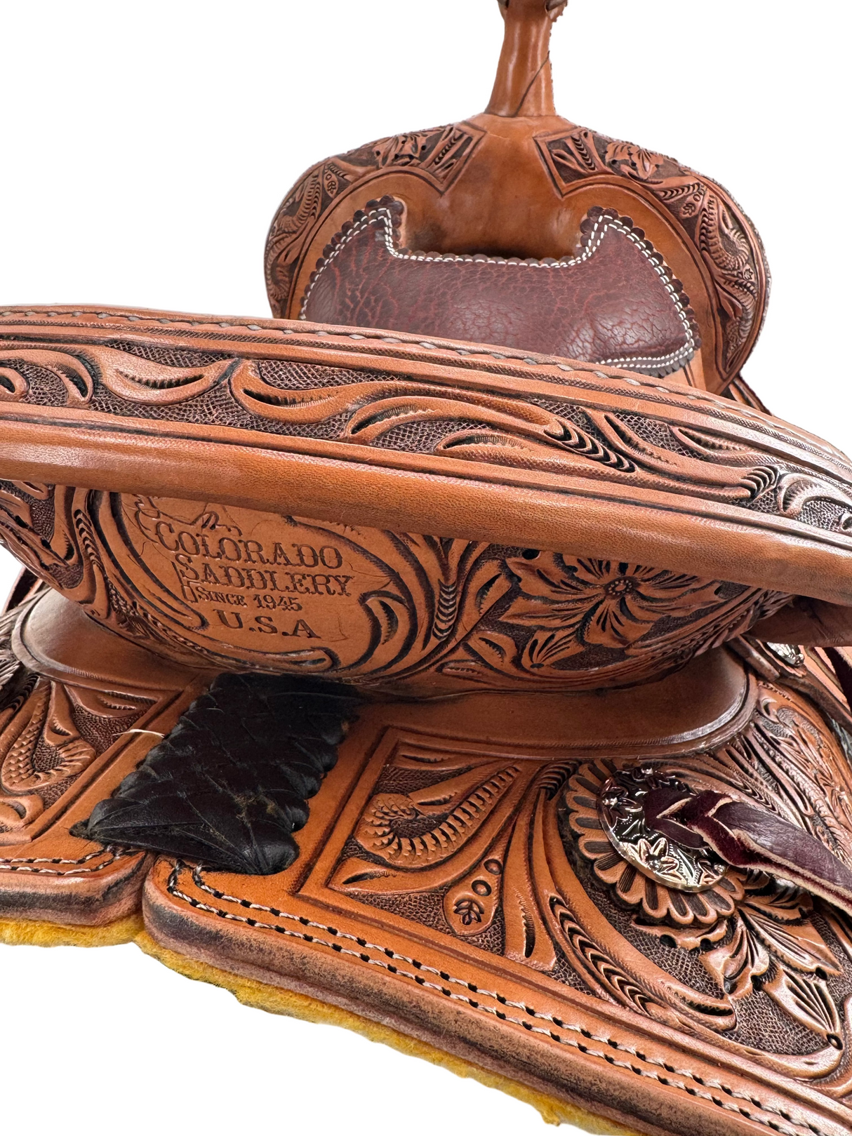 Close-up of a leather saddle with intricate designs and 'Colorado Saddle' branding.